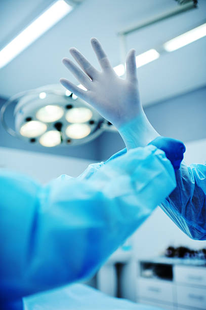 istock Assistant helps the surgeon put on latex gloves 612727972