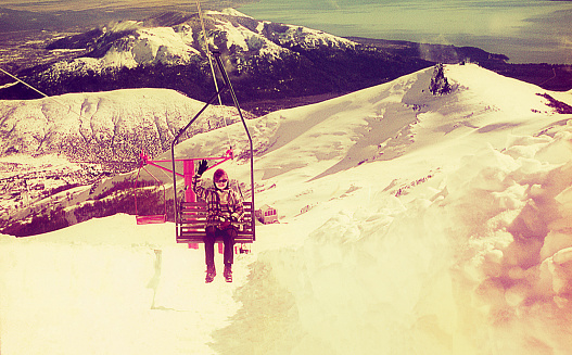 Vintage image featuring a woman climbing a snowy mountain on ski cable chair.