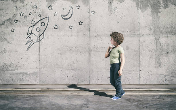 The young boy standing next to grey wall