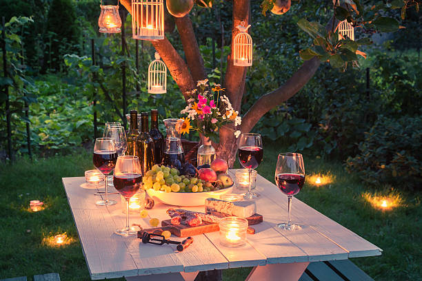 Beautiful table full of cheese and meats in garden Beautiful table full of cheese and meats in garden at dusk garden lights candle stock pictures, royalty-free photos & images