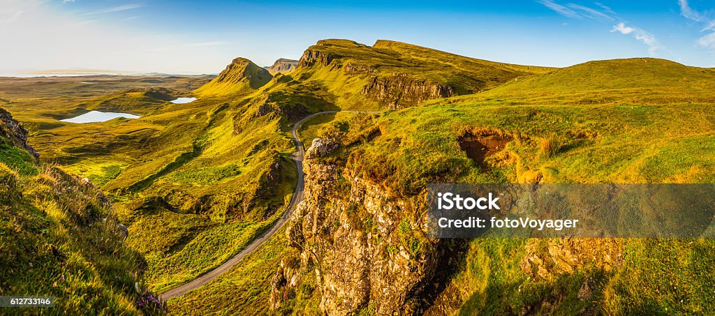 Scotland Isle of Skye country road idyllic Highlands mountains panorama Warm light of sunrise illuminating the dramatic rocky pinnacles, mountain peaks and vibrant valleys of the Quiraing, deep in the Highland wilderness of the Trotternish Penisula, Isle of Skye, Scotland. Scotland Stock Photo
