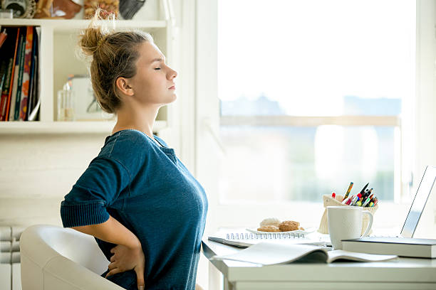 portrait of an attractive woman at the table backache pose - furniture internet adult blond hair imagens e fotografias de stock