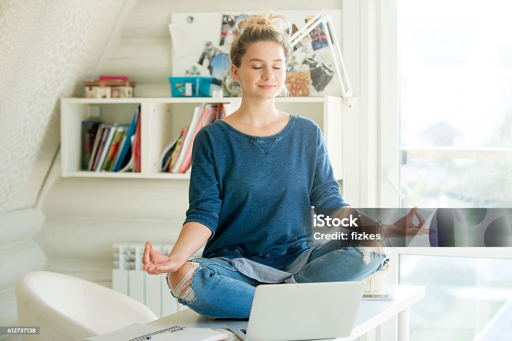 Portrait of an attractive woman at table , lotus pose Portrait of an attractive woman on the working table. Lotus pose. Motivation photo Zen-like Stock Photo