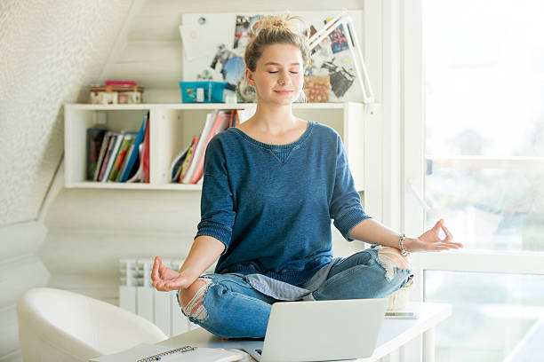 Portrait of an attractive woman at table , lotus pose Portrait of an attractive woman on the working table. Lotus pose. Motivation photo meditation room office stock pictures, royalty-free photos & images
