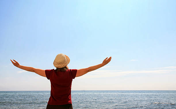 istock Woman raising arms at the beach 612737476