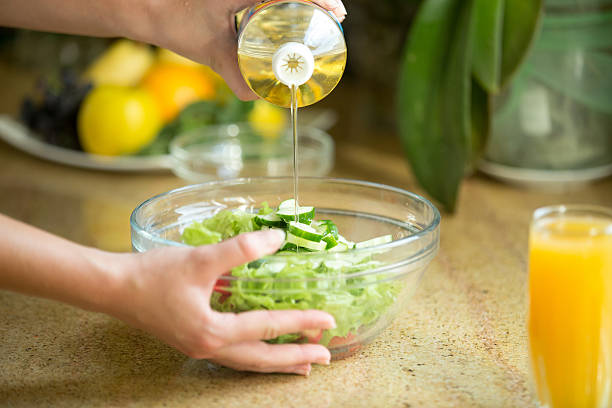 Hands pouring oil from the bottle in a green salad. Concept photo, closeup, close-up