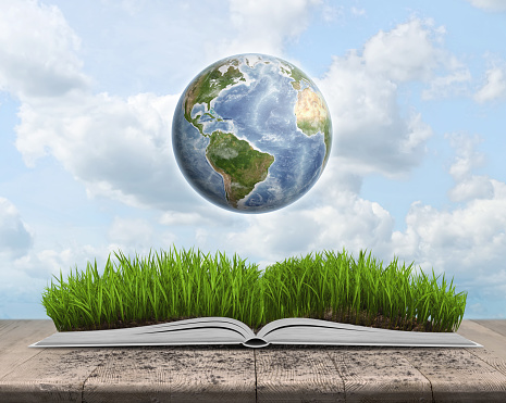 Green landscape covered by grass on an open book on sky background with Globe. Education and environment. Knowledge is power. Elements of this image are furnished by NASA. http://eoimages.gsfc.nasa.gov/images/imagerecords/73000/73726/world.topo.bathy.200406.3x5400x2700.jpg