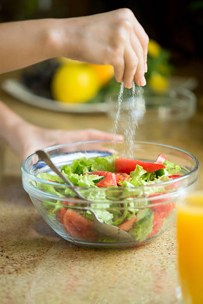 istock Hands salting a green salad 612737656