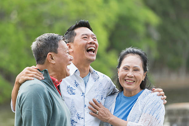 istock Asian man with senior parents in park laughing 612737930