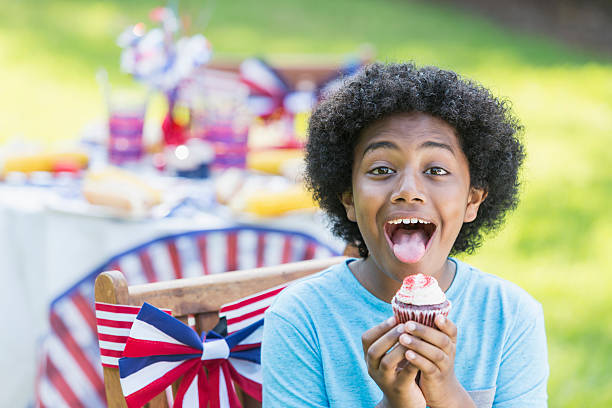 istock Mixed race boy having cupcake at 4th of July picnic 612738944