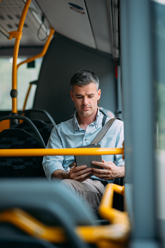 Businessman commuting to work by bus and working with a digital touch screen tablet