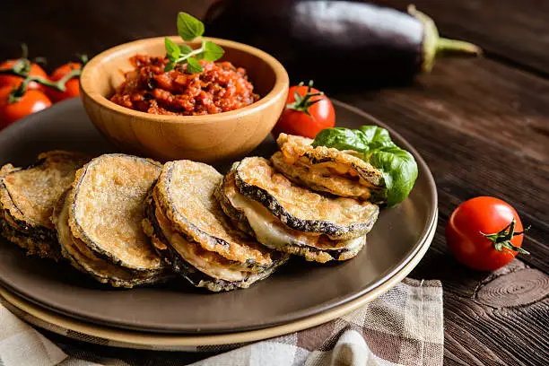 Roasted eggplant slices covered in egg, stuffed with Mozzarella, served with tomato salsa