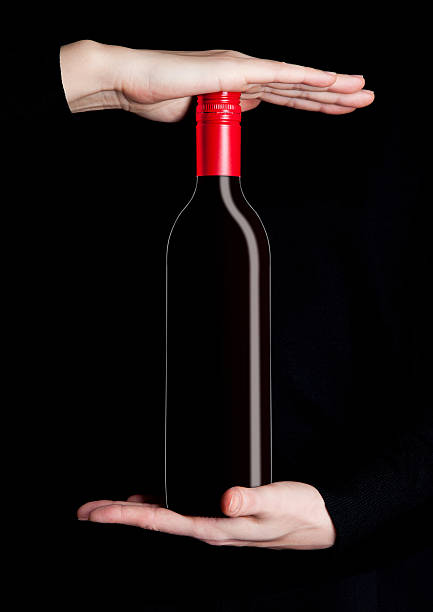 Woman hands holding bottle of red wine on black