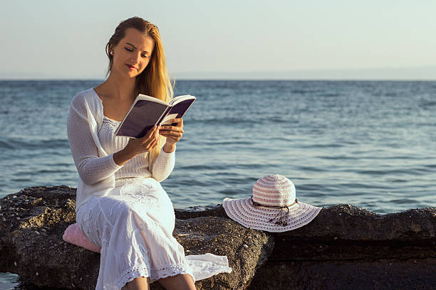 istock Young woman read book during beach vacation 612749998