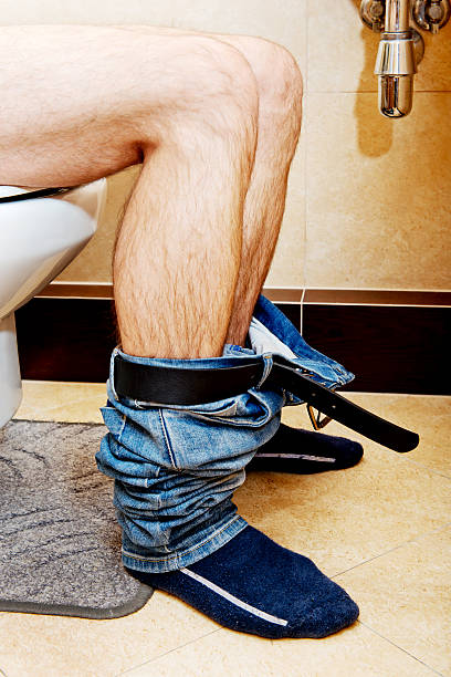 istock Man sitting on a toilet seat 612756484