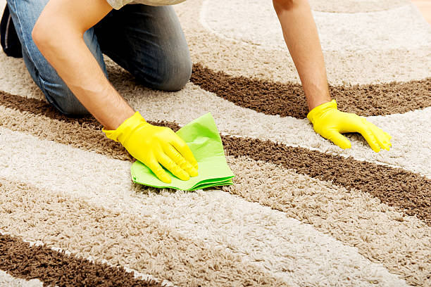 Man in yellow gloves cleaning carpet stock photo