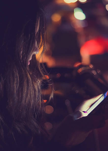 istock Girl using smart phone at night outdoors 612758900