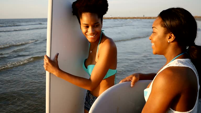 Two African American female friends prepare to go surfing