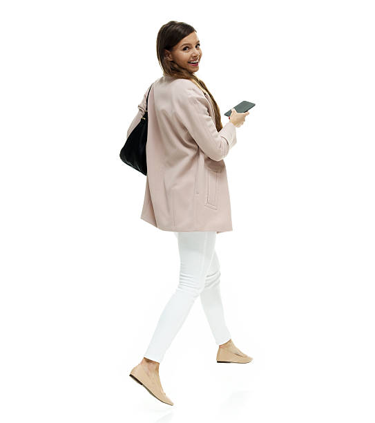 istock Smiling woman using phone and walking 612816688