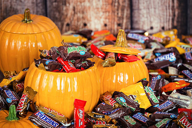 Decorative pumpkins filled with Halloween candy Dallas, United States - October 31, 2015: Decorative pumpkins filled with assorted Halloween chocolate candy made by Mars, Incorporated and the Hershey Company. confectionery stock pictures, royalty-free photos & images