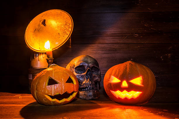 istock pumpkins with skull on wooden background with copy space 612817338