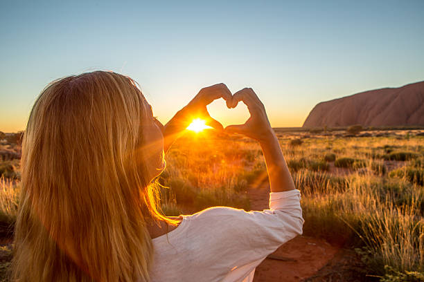 istock View of female framing sunset into heart shape 612822100