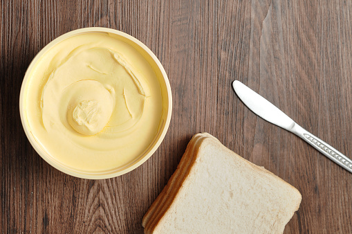 Butter, bread and a knife isolated on a wooden background