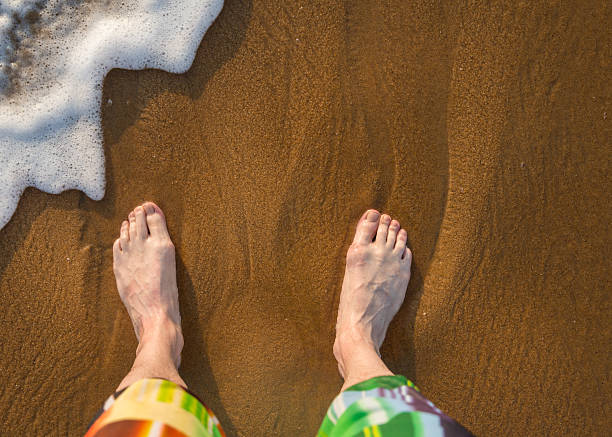 istock Male legs on sand 612825940