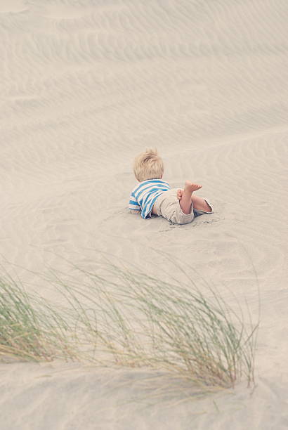 istock Child lies in the sand ripples on Beach 612829262
