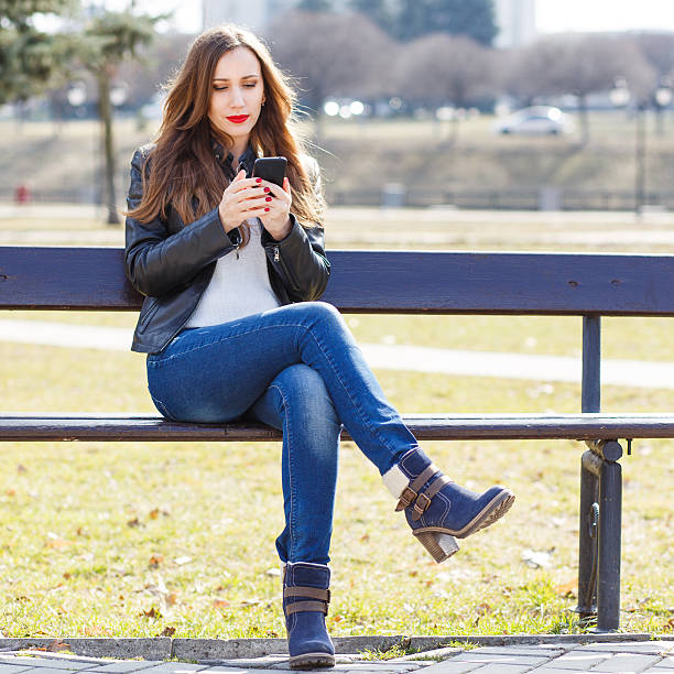 istock Young smiling woman using smartphone in park 612833098