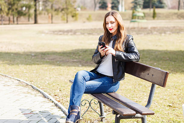 istock Young smiling woman using smartphone in park 612833226