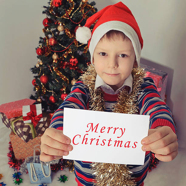 istock Boy holding greeting card. Christmastime 612833608