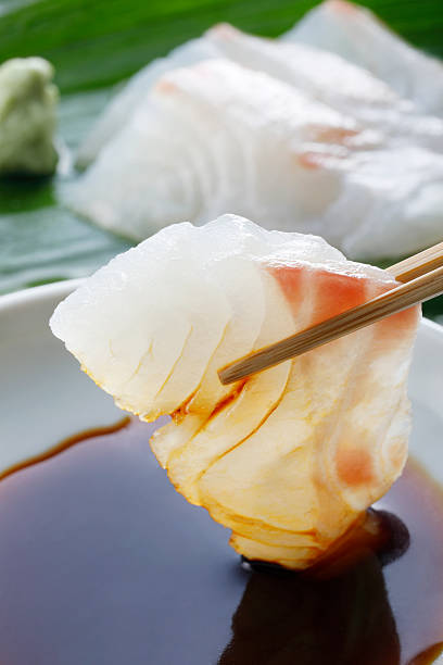 Put a sashimi in soy sauce with chopsticks