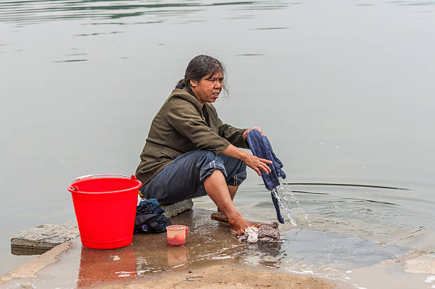 Yangshuo, China - October 20, 2013: Village in China, in countryside, rural Asian farm. Chinese peasant woman washing his clothes in water river near Yangshuo, China.