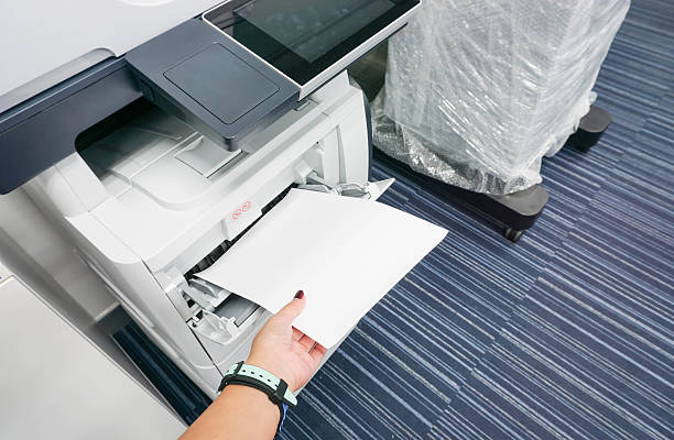 istock woman put stack of paper into printer 612837798
