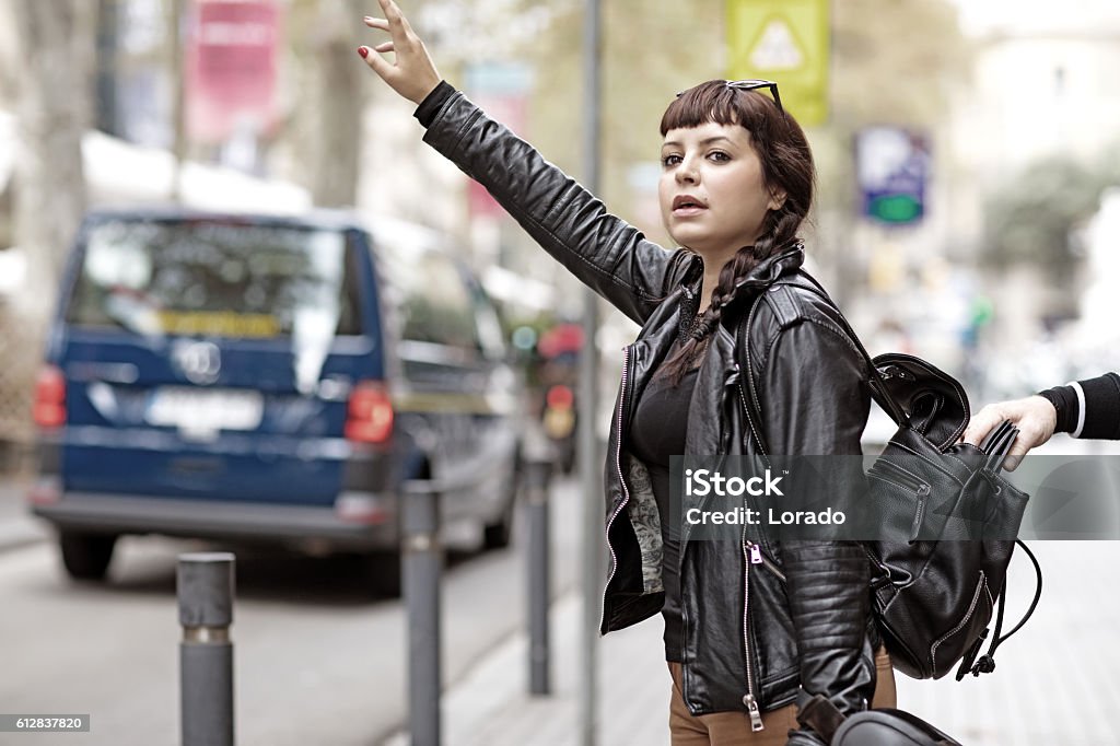 Distracted brunette female tourist and a pickpocket Distracted brunette female tourist hailing a taxi as a  pickpocket goes to work at stealing her purse Thief Stock Photo