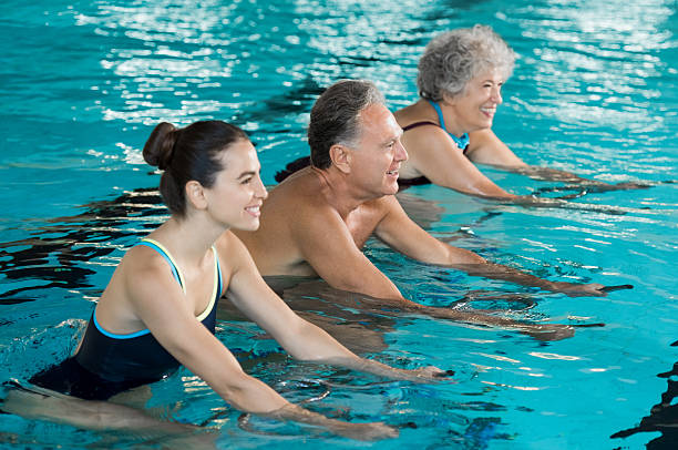 seniors cycling on aqua bike - spinning instructor exercising gym imagens e fotografias de stock