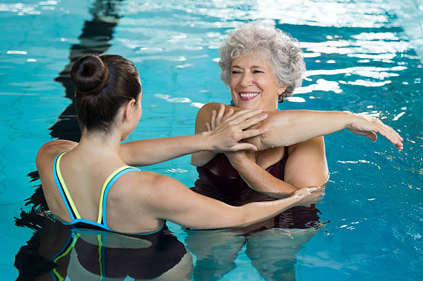 femme senior s’étirant dans la piscine - water aerobics swimming pool exercising sport photos et images de collection