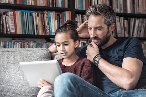 istock father and daughter at sofa with digital tablet 612840928