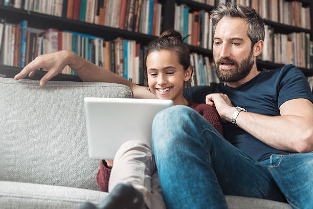 istock happy father and daughter at sofa with digital tablet 612840948