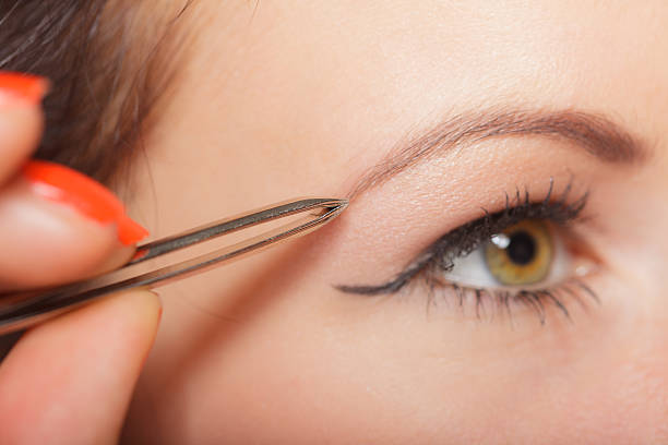 istock Girl tweezing eyebrows closeup 612841214