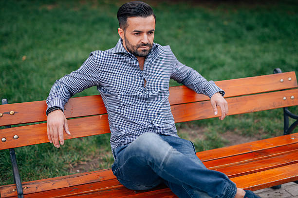 istock Elegant young man sitting on the bench 612842544
