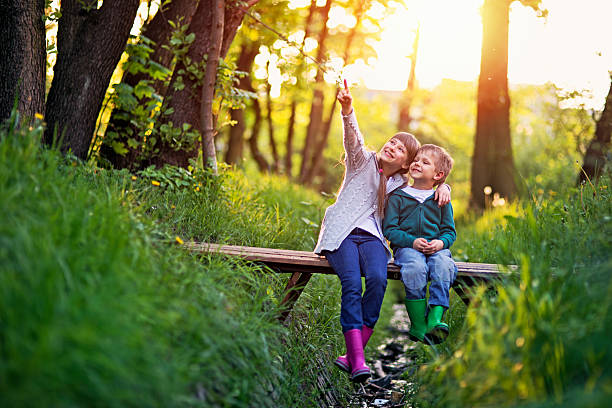istock Brother and sister sitting on bridge in forest 612843554