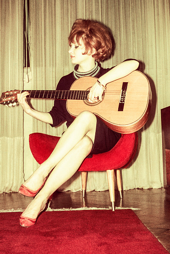 Vintage photo featuring a woman from the sixties playing guitar