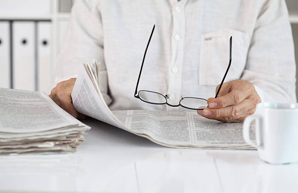 istock Man reading newspaper and holding eyeglasses 612844514
