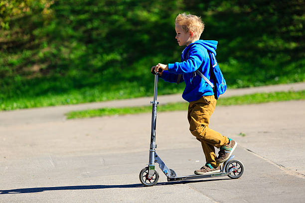 istock happy little boy riding scooter, active kids 612846342