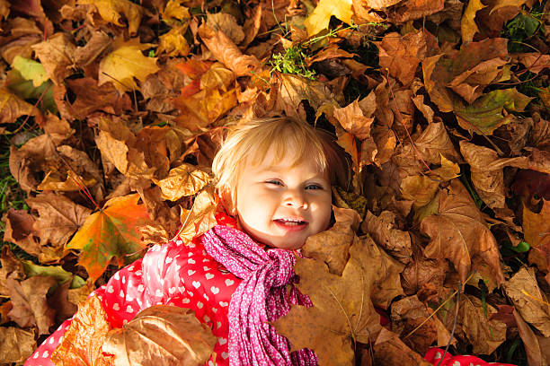 istock cute little girl playing with autumn fall leaves 612847416