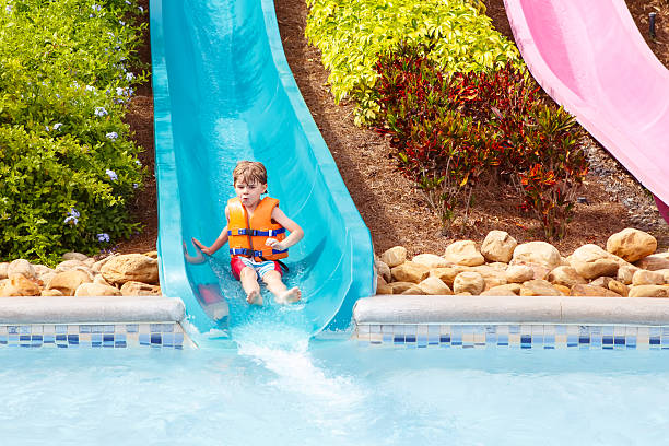 aufgeregtes kind im wasserpark reiten auf rutsche mit schwimmer - amusement park family water slide child stock-fotos und bilder