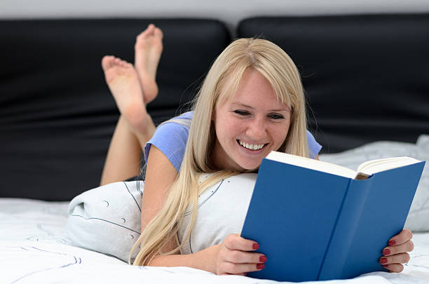 istock Young woman grinning as she reads a book 612850378