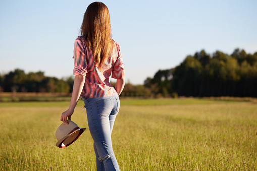 Standing girl in hat at cereals field in summer